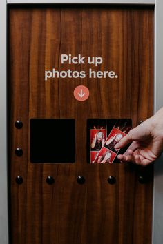 a person is pushing up photos here on a wooden paneled door that says pick up photos here