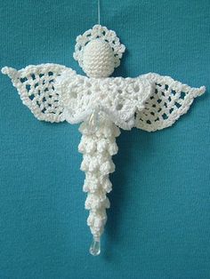 a crocheted angel ornament hanging on a blue background with white thread