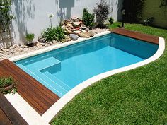 an empty swimming pool in the middle of a yard with grass and rocks around it