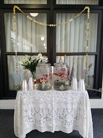 a table with vases and candles on it in front of a window covered by curtains