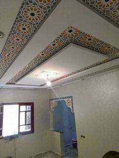 an empty room with white walls and decorative ceiling tiles on the ceiling, while sunlight shines through the window