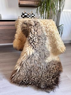 a sheepskin rug on the floor next to a potted plant