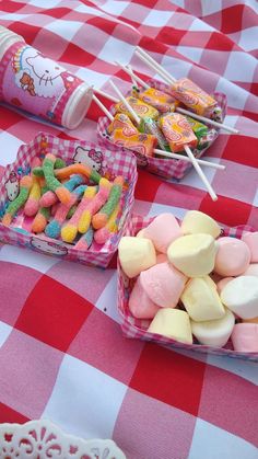 a table topped with candy and marshmallows on top of a checkered table cloth