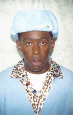 a young man wearing a blue hat and leopard print scarf