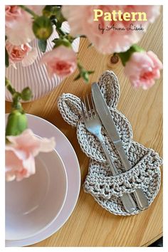 a crocheted placemat and fork on a table with pink flowers in the background