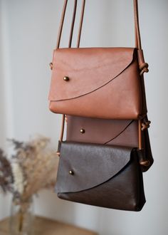 The Mini Asymmetrical Leather Bag - is handcrafted from soft, vegetable-tanned leather. Designed with a touch of simple elegance in mind, this compact wonder is your perfect partner for keeping your essentials right by your side. Whether it's your phone, keys, or small treasures, the gentle nature of the design ensures simplicity and comfort. Available in three hues - Tan, Brandy, and Chocolate Brown - it comes with a minimalist-style leather strap that can be customized to your preferred length Simple Leather Bag, Sac En Cuir Diy, Leather Bag Handmade, Handmade Leather Purse, Small Leather Purse, Crossbody Leather Bag, Leather Crossbody Bag Small, Leather Sling Bag, Mini Tote Bag