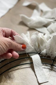 someone is sewing fabric on a piece of white material with orange nail polish and scissors