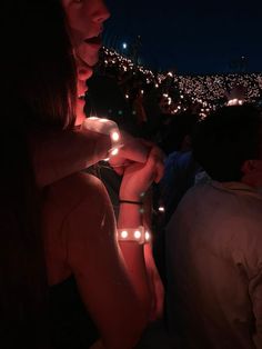 a woman standing in front of a group of people holding lit up lights at night