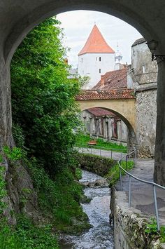 an arch in the side of a building with a river running under it and a clock tower on top