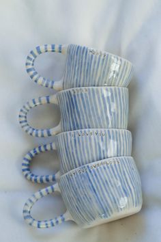 four blue and white striped coffee mugs stacked on top of each other