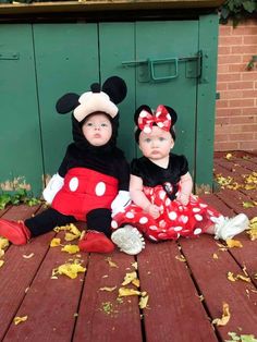 two toddlers dressed up as mickey and minnie mouse sitting on a deck with leaves