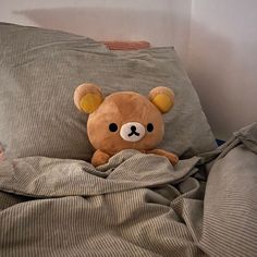 a brown teddy bear sitting on top of a bed