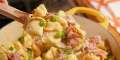 a spoon full of pasta with peas and ham