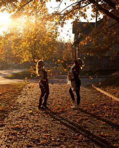 two people walking down a leaf covered road