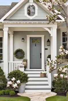 a white house with gray front door and steps leading up to the entryway area