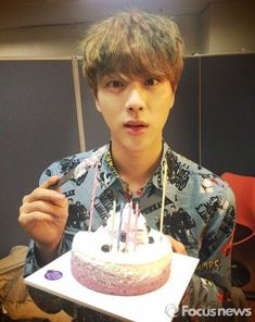 a young man holding a birthday cake with candles on it