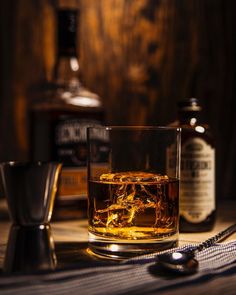 an old fashioned whiskey glass with ice cubes next to it