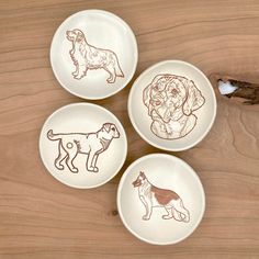 three bowls with dogs drawn on them sitting on a table