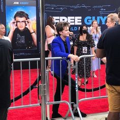 a man standing in front of a metal barricade at a movie event with people looking on