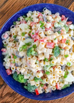 a blue bowl filled with macaroni salad on top of a wooden table