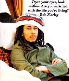 a man with dreadlocks is sitting on a couch wearing a knitted hat