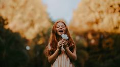 a girl with red hair holding a white flower and smiling at the camera, with a quote from st frances of assel above her