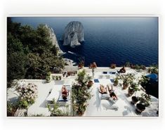 an aerial view of people lounging on the roof of a hotel overlooking the ocean