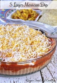 mexican dip in a glass dish with shredded cheese on top