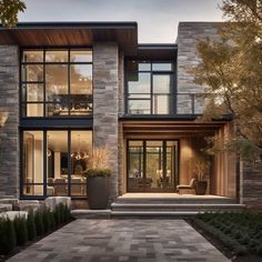 a modern house with large windows and stone walkway leading up to the front door area