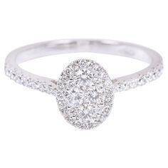 a white gold ring with diamonds on the band and an oval shaped center stone in the middle