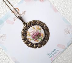 a necklace with a flower on it sitting on top of a white piece of paper