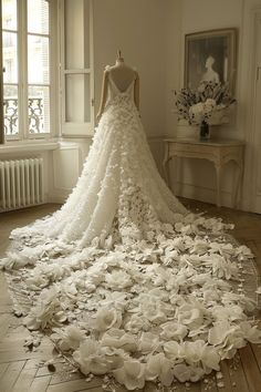 a wedding dress made out of flowers on the floor in front of an open window