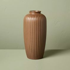 a large brown vase sitting on top of a table next to a green wall and floor