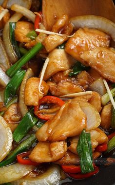 chicken and vegetables are being cooked in a wok with chopsticks on the side