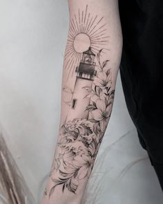 a woman's arm with a lighthouse and flowers on it