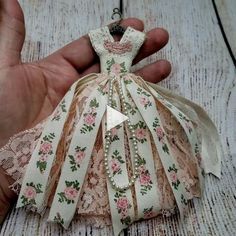 a hand holding a small doll made out of fabric and ribbon with flowers on it