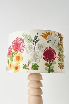 a lamp that has flowers on it with a wooden base and fabric shade over the top