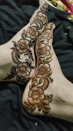 two feet covered in hendi with flowers and leaves painted on the bottom part of them