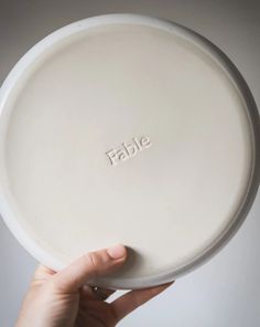 a person holding a white plate with the word table on it