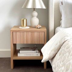 a nightstand with books and a lamp on it