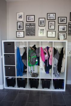 a white shelf filled with clothes next to pictures and framed photos on the wall above it