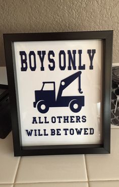 a framed sign that says boys only all others will be towed on the tile floor