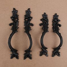 three black ornate handles on a brown background, one with an acantic design