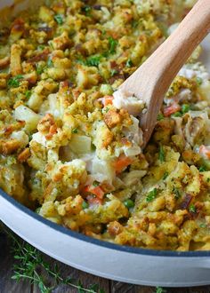 a wooden spoon in a pot full of stuffing and vegetables with parsley on the side