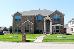 a large brick house sitting on top of a lush green field