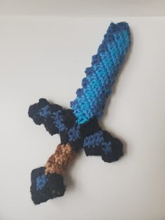 a crocheted blue and black object on a white surface with a brown cord