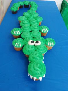 cupcakes with green frosting shaped like a crocodile's head on a blue table