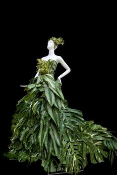 a mannequin dressed in a green dress made out of tropical leaves and plants