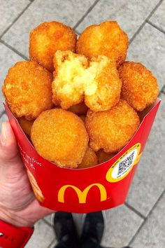 a person holding up a bucket full of fried food