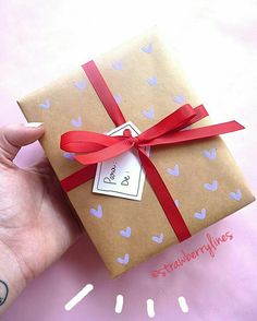 a hand holding a wrapped gift with a red ribbon and tag that says love on it